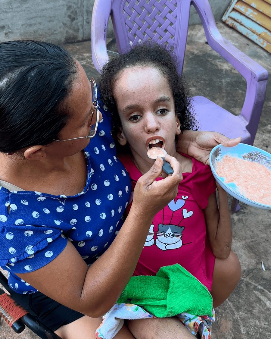 Ana Júlia no colo de Maria Sônia, que oferece comida a ela